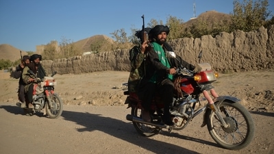 Taliban fighters patrol along a road on motorbikes at Ghasabha area in Qala-e-Now, Badghis province (AFP)