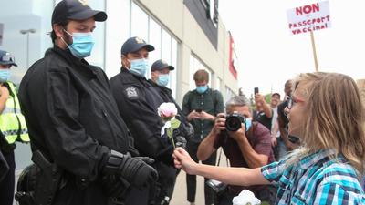 A protester gives roses to riot police members guarding the entrance to an Econofitness gym as people protest their use of a vaccine passport in Laval, Quebec, Canada. Quebec has pushed back Covid-19 vaccine mandates by a month. (REUTERS/File) A protester gives roses to riot police members guarding the entrance to an Econofitness gym as people protest their use of a vaccine passport in Laval, Quebec, Canada. Quebec has pushed back Covid-19 vaccine mandates by a month. (REUTERS/File)