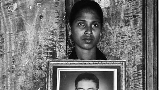 V Mary holds up an image of her late father, Anthony Swamy. This is from the award-winning First Witnesses series that uses the frame-within-a-frame to memorialise Indian farmers who have died by suicide, and their loved ones.(Photo: Vijay S Jodha )