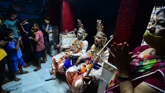 A devotee performs a ritual on youths dressed as Hindu God Rama and his companion Laxman sit inside a temple before a Dussehra festival procession, in Allahabad.(AFP)