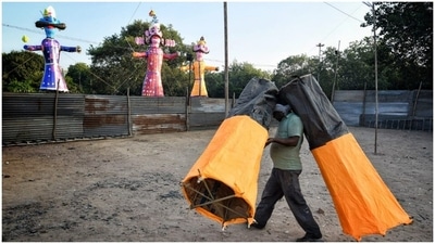 A worker carries a structure while the effigies of Ravana, Kumbhkaran and Meghnath can be seen installed. (HT Photos/ Sanchit Khanna) A worker carries a structure while the effigies of Ravana, Kumbhkaran and Meghnath can be seen installed. (HT Photos/ Sanchit Khanna)