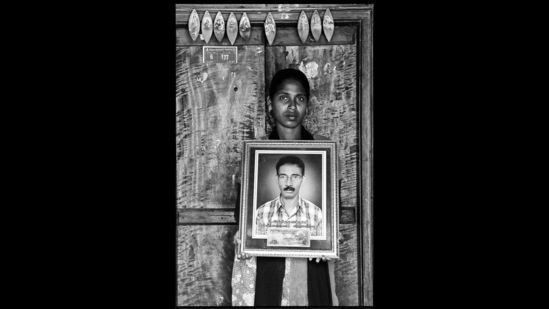 V Mary holds up an image of her late father, Anthony Swamy. This is from the award-winning First Witnesses series that uses the frame-within-a-frame to memorialise Indian farmers who have died by suicide, and their loved ones.(Photo: Vijay S Jodha)