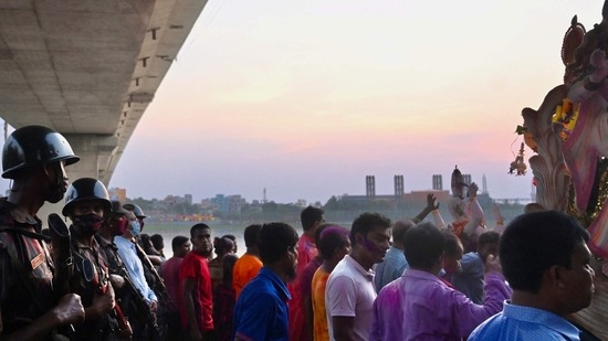 Border Guard Bangladesh personnel stand guard as devotees prepare to immerse a clay idol of the Goddess Durga in the Buriganga River on the final day of the Durga Puja festival in Dhaka.&nbsp;(AFP)