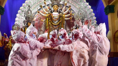 Devotees in a Kolkata pandal wear PPE kit and exchange vermillion with each other as a part of rituals during Vijayadashami. (PTI) Devotees in a Kolkata pandal wear PPE kit and exchange vermillion with each other as a part of rituals during Vijayadashami. (PTI)