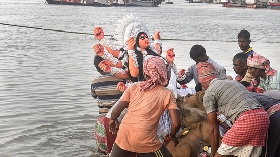 Devotees immerse an idol of Goddess Durga on the last day of Durga Puja festival at the bank of river Ganga in Kolkata.(PTI)