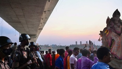 Border Guard Bangladesh personnel stand guard as devotees prepare to immerse a clay idol of the Goddess Durga in the Buriganga River on the final day of the Durga Puja festival in Dhaka. (AFP)&nbsp;