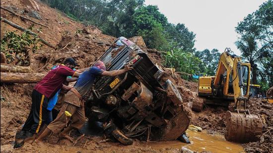 Rescue workers push an overturned vehicle stuck in the mud after a landslide in Kerala’s Kokkayar, on Sunday. Kerala rain toll has increased to 24. (AFP)