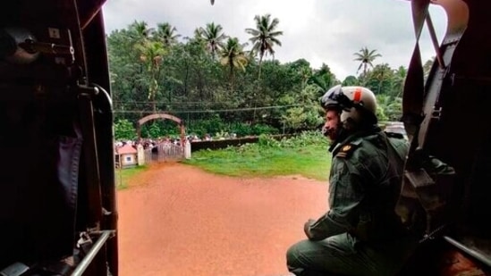 A navy person looking from their helicopter on a mission to distribute relief material to flood affected people at Koottickal in Kottayam district of Kerala.(AP)