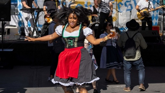 A women holds a beer while dancing in costume to the polka band, West Coast Prost, at the Vegan Oktoberfest beer festival in Los Angeles on October 16.(AFP)