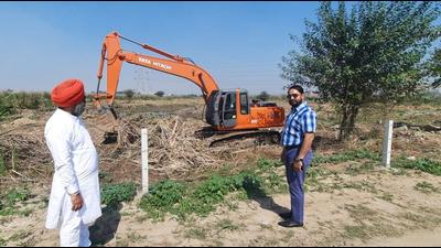 Mohali mayor Amarjit Singh Sidhu (right) overseeing the clearance of the land for the cow sheds in Sector 91, Mohali. (HT Photo)