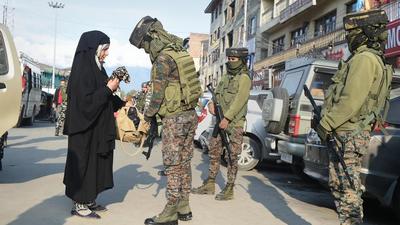Women security personnel frisk a pedestrian in Srinagar as security is tightened following the recent civilian killings. (PTI Photo)