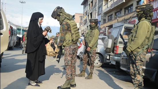 Women security personnel frisk a pedestrian in Srinagar as security is tightened following the recent civilian killings. (PTI Photo)