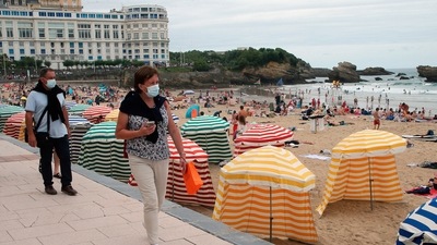 People wear face masks, to protect against coronavirus, walk on the pedestrian promenade along the beach in Biarritz, southwestern France. (AP File) People wear face masks, to protect against coronavirus, walk on the pedestrian promenade along the beach in Biarritz, southwestern France. (AP File)