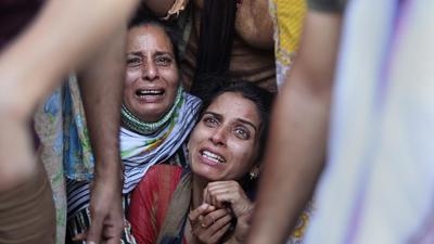 Aradhana (centre), wife of Deepak chand, a school teacher who was killed in Kashmir, mourns the death of her husband (AP)