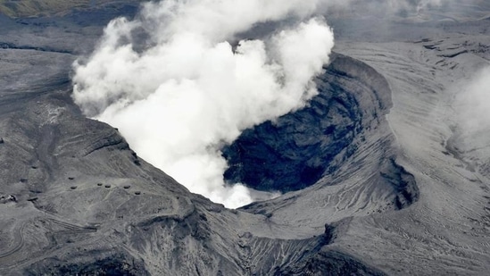 Houses are covered in volcanic ash from the eruption of Mount Aso, top, in Aso city,&nbsp;(AP)