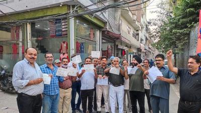 Members of the Punjab Pradesh Beopar Mandal tear copies of the notification of professional tax during a protest against the state government in Ludhiana on Thursday. (HT Photo)