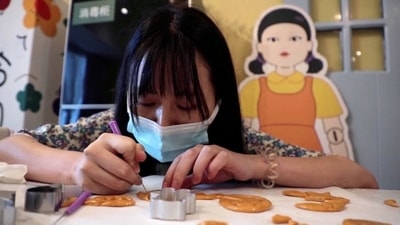 A customer uses a tool to cut a biscuit into a shape during a session of a South Korean Netflix show Squid Game-themed confection-making event, at a bakery in Beijing, China. (REUTERS)
