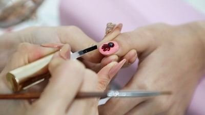 Nail artist works on a Squid Game's manicure for a client at her shop in Kuala Lumpur, Malaysia. (REUTERS)