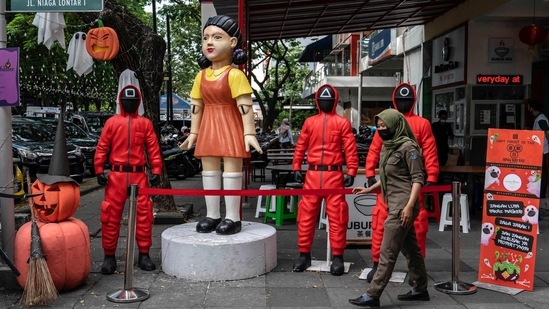 A woman walks past statues featuring characters from the Netflix series Squid Game at a food court to attract visitors in Surabaya.(AFP)