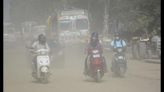 Commuters pass through a dusty road in Ghaziabad on Saturday. (Sakib Ali/HT)
