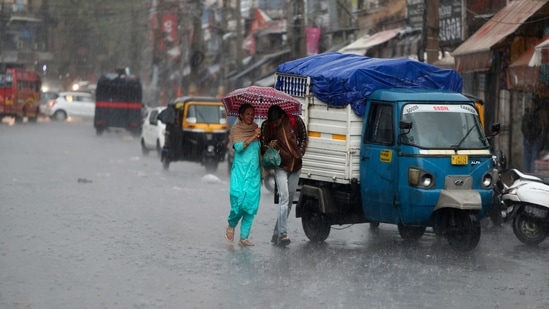 People walk in the rain in Jammu on Saturday, October 23. The Jammu-Srinagar highway, that connects Kashmir valley to the rest of India, remained closed for traffic as higher reaches of Kashmir received fresh snowfall while heavy rains lashed the plains. (AP)