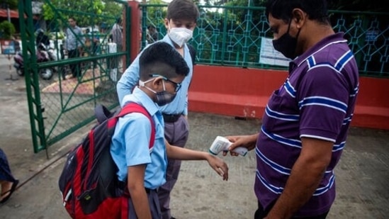 A school staff checks temperature of a student at a school.(AP Photo/Anupam Nath)