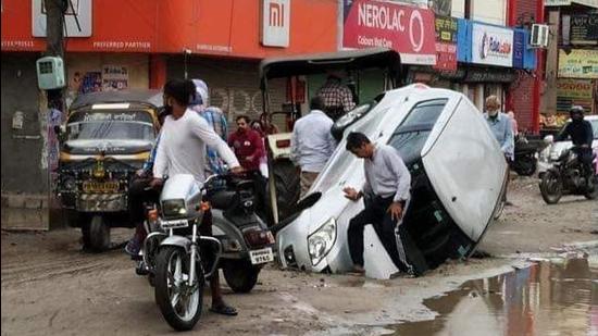 The car stuck in a 4-ft deep and 9-ft wide road cave-in at Haibowal in Ludhiana on Sunday morning. (HT Photo) The car stuck in a 4-ft deep and 9-ft wide road cave-in at Haibowal in Ludhiana on Sunday morning. (HT Photo)