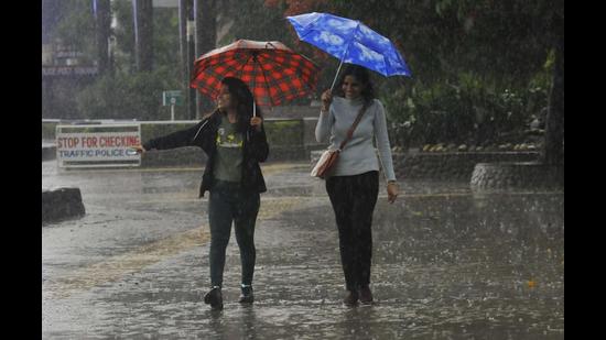 Shielding themselves with woollens and umbrellas, women enjoying the rain at Sukhna Lake in Chandigarh on Sunday. (Keshav Singh/HT)