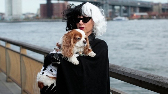 A lady dresses up as Cruella De Vil and holds her dog as they attend the annual Tompkins Square Halloween Dog Parade at East River Park Amphitheater in New York.(AFP)