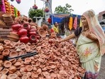 A vendor arranges earthen lamps at her shop ahead of Diwali in Ahmedabad on Monday. (PTI Photo)