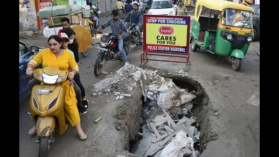 Commuters try to navigate around the stretch where a portion of the road had caved-in on Hambran road in Ludhiana. In another oart of the city, a resident fell into a manhole. Show-cause notices issued to two contractors. (HT File)