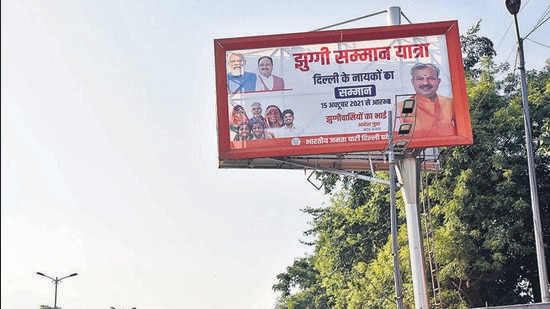 Jhuggi Samman Yatra board displayed near IIT, in New Delhi. Earlier this month, BJP MP Manoj Tiwari met with puja committees and held rath yatra in areas with a large presence of the Purvanchali community to galvanise support. (Sanjeev Verma/HT PHOTO)