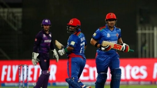 Afghanistan's Hazratullah Zazai, right, and Mohammad Shahzad run between the wickets to score during the Cricket Twenty20 World Cup match between Afghanistan and Scotland in Sharjah, UAE, Monday, Oct. 25, 2021.(AP)