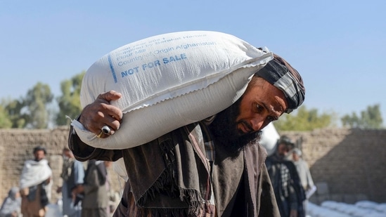 Afghan people carry sacks of food grains distributed as aid by the World Food Programme (WFP) in Kandahar.(AFP)