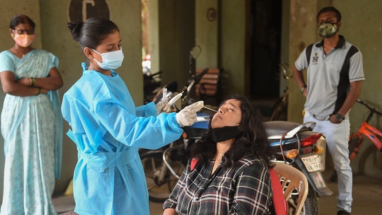 A health worker collects swab sample of a resident for Covid test in Mumbai on Tuesday.(PTI) A health worker collects swab sample of a resident for Covid test in Mumbai on Tuesday.(PTI)