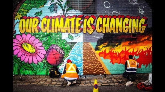 Street artists paint a mural on a wall opposite the COP26 climate summit venue in Glasgow, October 13, 2021 (AFP)