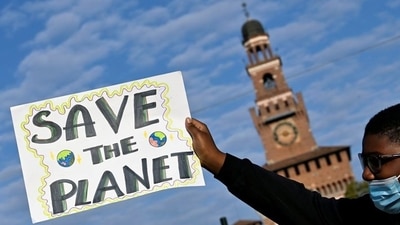 A protester holds up a sign during a climate strike in Milan. (REUTERS)
