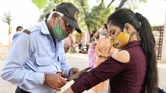 A security guard cuts a sleeve of top worn by a female candidate as she arrives to appear for the Rajasthan Administrative Services (RAS) 2021 prelims exam at an examination centre, in Bikaner.(ANI/Dinesh Gupta)