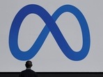 A man stands in front of a sign of Meta, the new name for the company formerly known as Facebook,