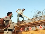 Police personnel supervises the removal of barbed wire from barricades at the Ghazipur border on Friday. (ANI Photo)(Amit Sharma) Police personnel supervises the removal of barbed wire from barricades at the Ghazipur border on Friday. (ANI Photo)(Amit Sharma)