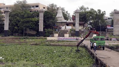 A PMC team removes water hyacinth from Mutha river in Pune. The state irrigation department has issued a letter to PMC warning the civic body about making changes to the city’s rivers against the background of the planned riverfront development project. (HT FILE )