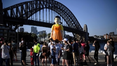 People on social media are sharing Squid Game related content and receiving good response from their fans. In Sydney, a 4.5 metre tall replica doll from the Squid Game has installed at the harbour and fans and rushing to take pictures with the doll. (AFP) People on social media are sharing Squid Game related content and receiving good response from their fans. In Sydney, a 4.5 metre tall replica doll from the Squid Game has installed at the harbour and fans and rushing to take pictures with the doll. (AFP)