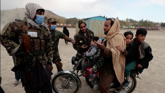 Taliban fighters talk to a man riding a motorcycle with his children as they visit the amusement park at Kabul’s Qargha reservoir, Afghanistan on Friday. India and the United States called upon the Taliban once again to ensure terrorists never use Afghan soil to launch attacks on any country. (REUTERS)