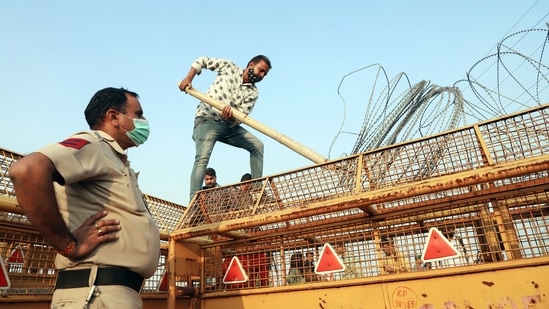 Police personnel supervises the removal of barbed wire from barricades at the Ghazipur border on Friday. (ANI Photo)(Amit Sharma)