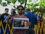A fan stands with a poster of Bollywood actor Shah Rukh Khan and his son Aryan Khan outside his residence. A fan stands with a poster of Bollywood actor Shah Rukh Khan and his son Aryan Khan outside his residence. 