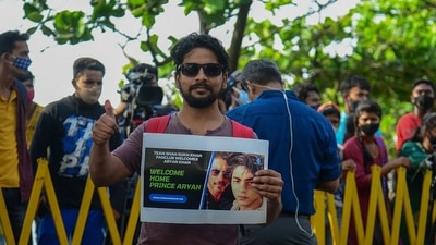 A fan stands with a poster of Bollywood actor Shah Rukh Khan and his son Aryan Khan outside his residence. (AFP Photo) A fan stands with a poster of Bollywood actor Shah Rukh Khan and his son Aryan Khan outside his residence. (AFP Photo)