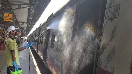 A worker sanitises a compartment of a local train at Sealdah Railway station in Kolkata on the eve of the resumption of its services with 50 per cent capacity.(PTI)