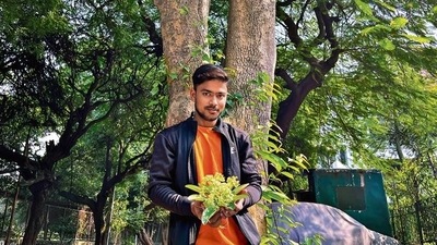 The photo shows Gufran Siddqui, a chauffeur, holding flowers under a saptaparni tree in central Delhi. The photo shows Gufran Siddqui, a chauffeur, holding flowers under a saptaparni tree in central Delhi.