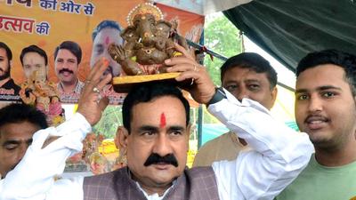 A file photo of Madhya Pradesh home minister Narottam Mishra carrying the idol of Lord Ganesha on the occasion of the Ganesh Chaturthi festival in Bhopal. (ANI/File)