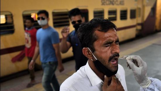 A health worker collects a swab sample for a Covid-19 test from a passenger arriving on outstation trains at Dadar station in Mumbai recently. (Satish Bate/HT file photo)